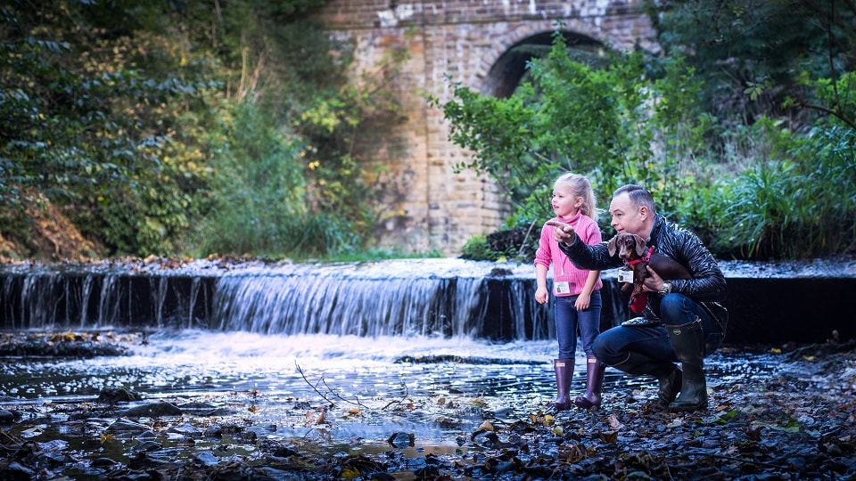 Man with daughter and dog next to a river